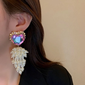 Close-up of model wearing vintage heart-shaped rhinestone and white pearl tassel earrings