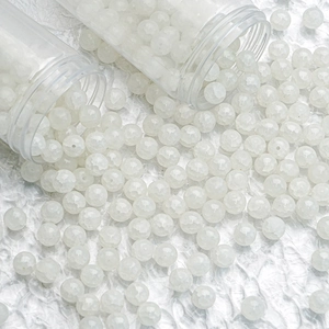 Macro shot of 10mm white ice-crackled glass beads spilling from plastic tubes for DIY