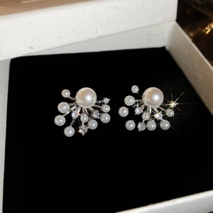 Macro shot of silver pearl earrings with zircon fireworks design in a luxury jewelry gift box