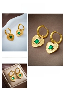 Macro detail of heart charm earrings with radial texture and square green zircon inlay
