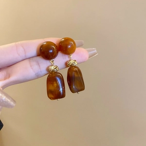 Detail of amber resin drop earrings featuring irregular geometric shapes and gold knots