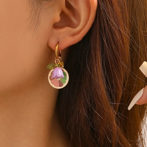 Macro di orecchino alla moda con fiore viola e fette di frutta colorate su una modella