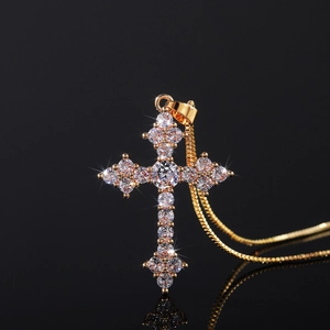 Macro view of a gold cross pendant set with sparkling cubic zirconia on a black background