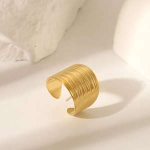 Macro detail of golden irregular wide ring featuring fine linear texture and metallic luster