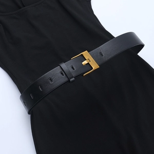Detail of a black faux leather belt with a golden metal buckle on a slim jumpsuit