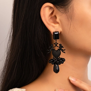 Détail de boucles d'oreilles vintage cœur noir avec perles et cupidon sur un mannequin