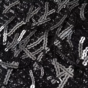 Macro shot of silver sequins on black mesh fabric for a stylish fringe mini dress