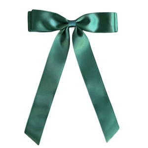 Detailed view of dark green satin bow hair clip with elegant long ribbon tails