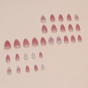 Almond press-on nails with pink gradient, 3D floral accents, and pearl decorations