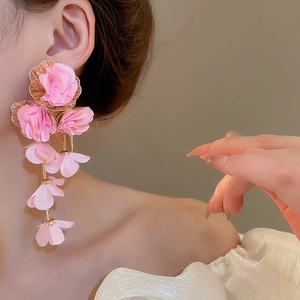 Close-up of pink chiffon flower drop earrings with golden base on a female model