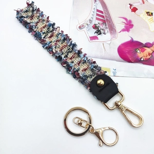 Detail of colorful woven wrist strap with gold carabiner and leather fastener