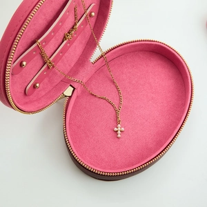 Brown oval jewelry box with pink velvet interior and gold zipper detailing