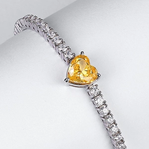 Vista macro di un bracciale a cuore in argento con gemme trasparenti e pietra gialla