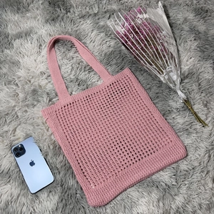 Detail of pink knitted hollow-out tote bag showing woven texture and soft pink yarn