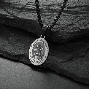 Black stainless steel Saint Michael pendant necklace on a textured dark rock background