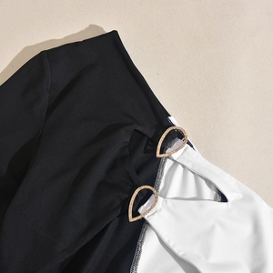 Détail d'une robe patchwork noir et blanc avec deux anneaux dorés martelés