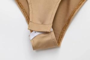 Détail de la fermeture à boutons-pression et coutures renforcées d'un body en satin