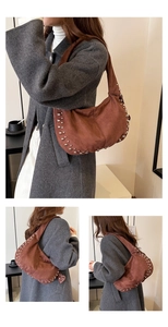 Detail view of brown suede shoulder bag with silver rivet studs in a minimal studio setting
