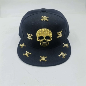 Detailed close-up of a black snapback hat featuring golden metal skull and spike studs