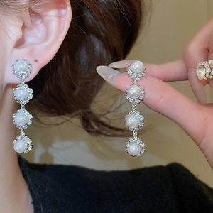 Detail showing elegant flower-shaped silver earrings with pearls and crystal rhinestones