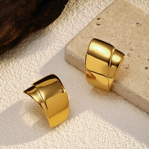 Detail view of polished 18K gold-plated curved stud earrings on natural stone background