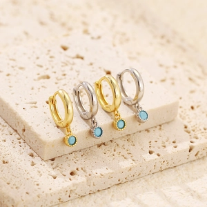 Close-up of gold and silver S925 sterling silver huggie hoop earrings with turquoise charms