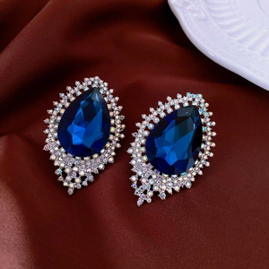 Detailed view of pear-cut blue gemstone earrings with rainbow rhinestones on silk