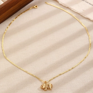 Detailed close-up of a golden elephant pendant necklace on a rustic textured surface
