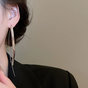 Polished silver teardrop earrings on model with elegant minimalist linear design