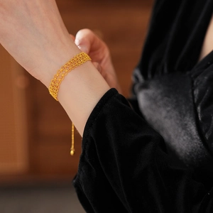 Detailed view of a gold-plated lace hollow bracelet with bead clasp on a model's wrist