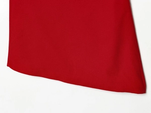 Vue détaillée de l'ourlet asymétrique et du tissu rouge uni du haut décontracté