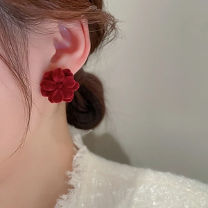 Close-up of a model wearing a vintage deep red flocked flower stud earring for autumn