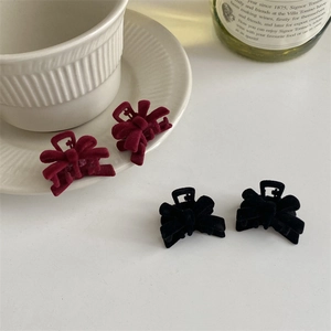 Detail of mini velvet bow hair clips in burgundy and black with soft flocked texture