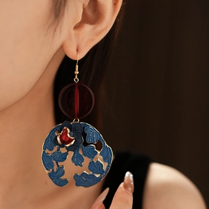 Close-up of vintage golden earring with red rose motif and blue cutout leaf detail
