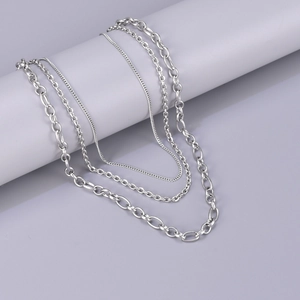 Silver multi-layer stainless steel necklace with curb and snake chains on grey stand