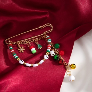 Détail d'une broche de Noël avec perles Holly et pompons sur tissu en soie rouge