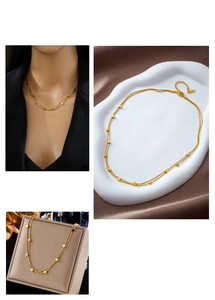 Detail of layered gold stainless steel necklace with polished geometric square charms
