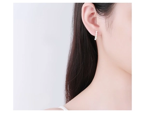 Detail view of model wearing minimalist S925 silver earrings with five small white pearls