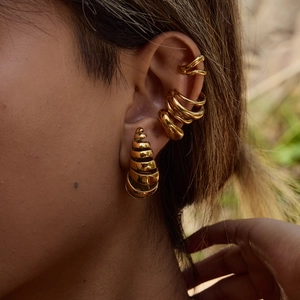Golden spiral hoop earrings with pearl ear cuffs shown on a model for a layered luxury look