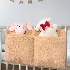 Close-up of brown teddy fleece baby crib storage bag with two pockets and soft plush toys