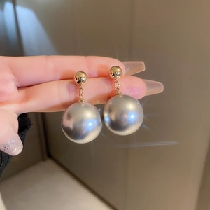 Detailed view of grey pearl drop earrings with gold plated studs and starburst lighting