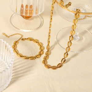 Ensemble collier et bracelet dorés au design coquillage sur fond beige élégant