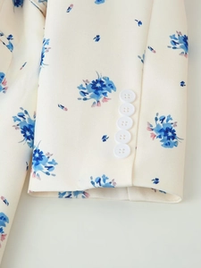 Detailed close-up of white floral blazer sleeve featuring five white buttons and blue prints