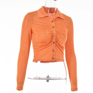 Detailed view of an orange long-sleeve shirt with lapel collar and pleated waist design