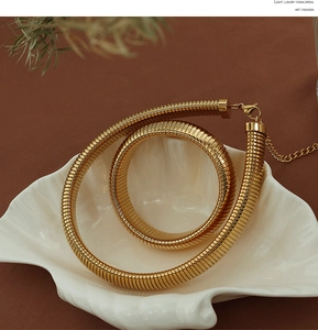 Close-up of golden thick snake chain necklace with lobster clasp on shell tray