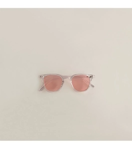 Gros plan de lunettes de soleil enfant avec verres roses et monture transparente beige