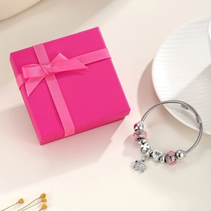 Detailed view of silver crown charm bracelet with pink beads and cute elephant pendant in a box