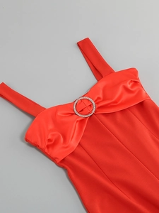 Detail eines roten Trägerkleids mit Kristallschließe und Satin-Faltendesign am Brustkorb