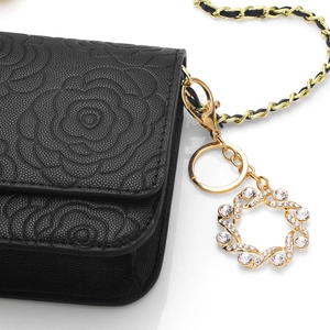 Borsa in pelle goffrata nera con motivo a camelia e ciondolo dorato con strass