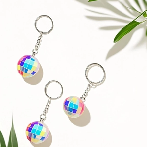 Three iridescent disco ball keychains with metallic rings on a minimalist white surface